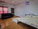 Spacious bedroom with a double bed, sofa, and wooden floor