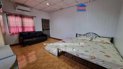 Spacious bedroom with a double bed, sofa, and wooden floor