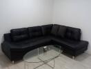 Modern living room with black leather sectional sofa and glass coffee table