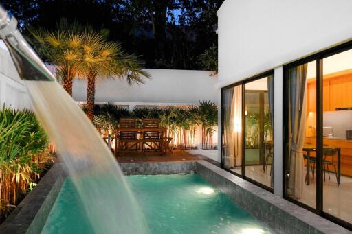 Luxurious outdoor pool with adjacent dining area and illuminated living space