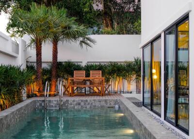 Modern outdoor pool area with lounge chairs and palm trees next to a residential building