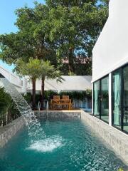 Elegant outdoor pool with waterfall feature and seating area