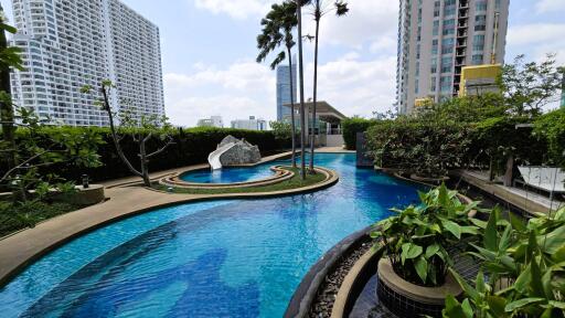 Luxurious pool area with lush greenery and modern sculpture surrounded by high-rise buildings