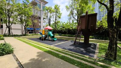 Well-maintained playground surrounded by lush greenery in residential complex