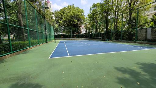 Tennis court surrounded by lush greenery in residential community