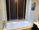 Modern bathroom with a white bathtub and wooden blinds