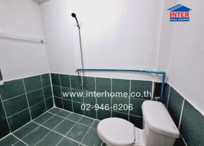 Modern bathroom with green tiles, white fixtures, and accessibility features