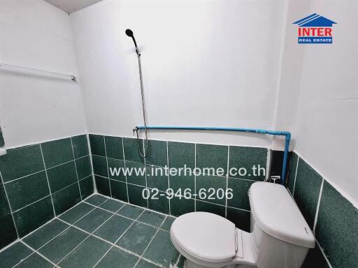 Modern bathroom with green tiles, white fixtures, and accessibility features