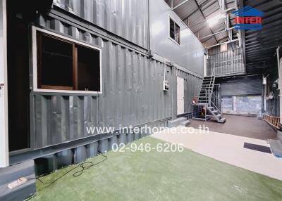 Industrial warehouse interior with green floor and metal staircase