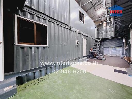 Industrial warehouse interior with green floor and metal staircase