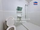 Compact white tiled bathroom with toilet, sink, and shower