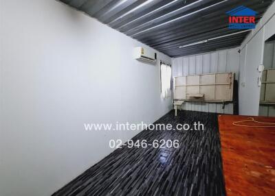 Spacious semi-outdoor covered area with corrugated metal roof and wooden flooring