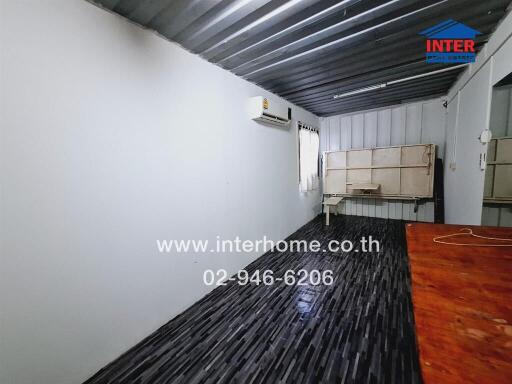 Spacious semi-outdoor covered area with corrugated metal roof and wooden flooring