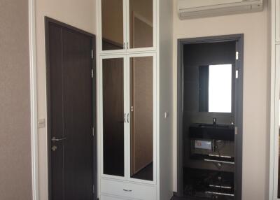 Bedroom with dark wardrobe, white folding doors, and air conditioning unit