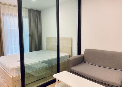 Modern bedroom with glass partition featuring a bed and a sofa