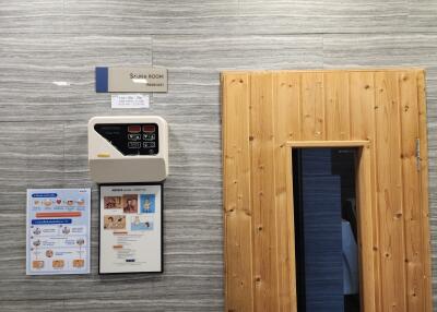 Interior view of a sauna room showing wooden door and informational posters on the wall