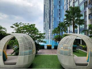Luxurious pool area with modern woven cocoon chairs and urban high-rise backdrop