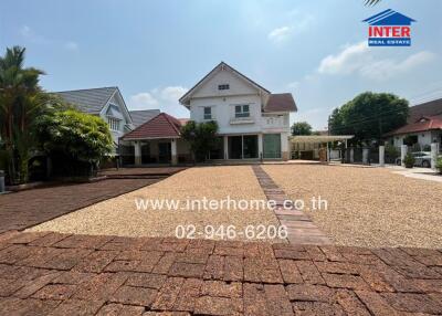 Front view of a large white house with spacious brick driveway