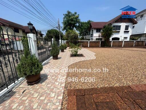 Paved courtyard with ornate metal gate and landscaped planters in a residential area