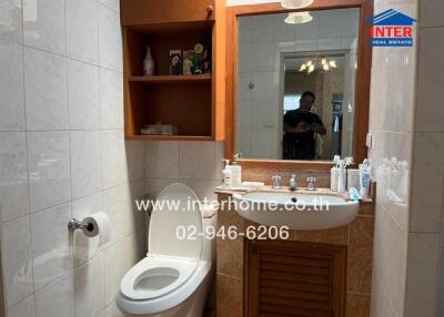 Compact bathroom featuring a toilet, sink, mirror, and storage shelves