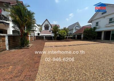 Well-maintained exterior view of residential community with paved driveway and tropical landscaping