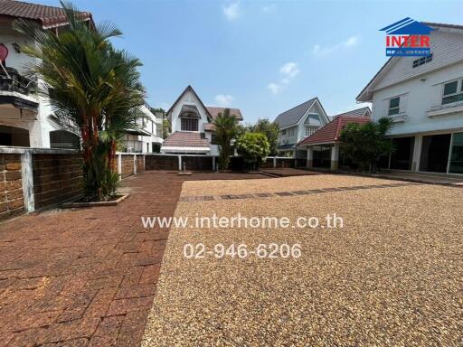 Well-maintained exterior view of residential community with paved driveway and tropical landscaping