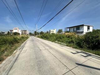 Wide street view with surrounding residential buildings under a clear blue sky