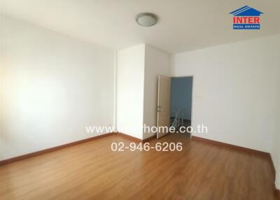 Empty bedroom in a modern home with wooden flooring and white walls