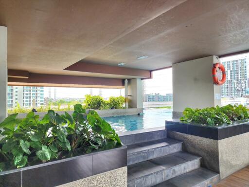 Spacious pool area with city skyline view and lush green plants