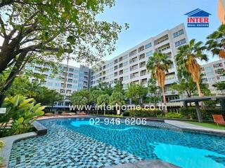 Lush outdoor swimming pool surrounded by palm trees and adjacent to modern residential buildings