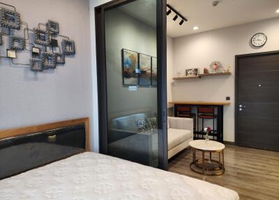 Modern bedroom with glass partition leading to a cozy sitting area