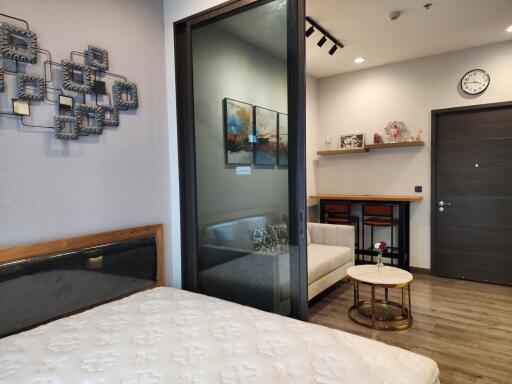 Modern bedroom with glass partition leading to a cozy sitting area