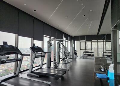 Modern high-rise building gym with cardio machines and weights overlooking the city