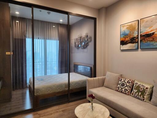 Modern bedroom with sliding glass doors, cozy sofa, and wall art