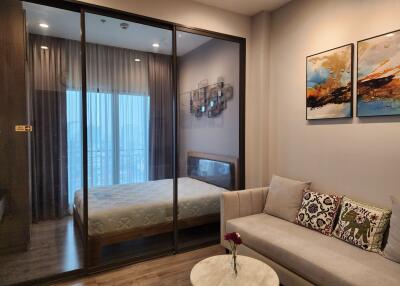 Modern bedroom with sliding glass doors, cozy sofa, and wall art