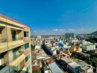 City view from apartment building balcony showing dense urban landscape under clear blue sky