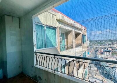 View from a tiled balcony overlooking a cityscape with safety netting