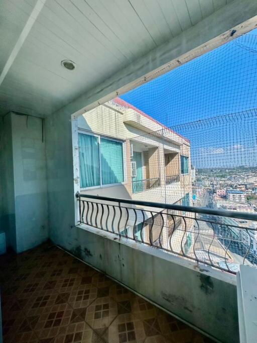 View from a tiled balcony overlooking a cityscape with safety netting