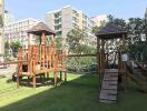 Spacious outdoor common area with wooden play structures and lush greenery in a residential apartment complex