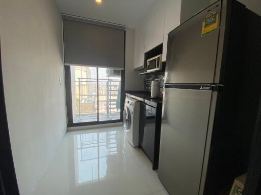 Modern apartment kitchen with large fridge and washing machine