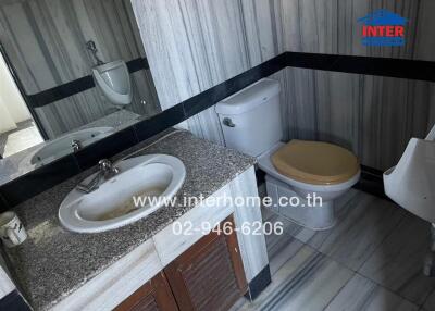 Compact bathroom with marble walls and wooden cabinet