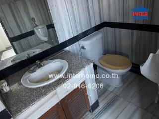 Compact bathroom with marble walls and wooden cabinet