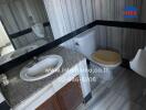 Compact bathroom with marble walls and wooden cabinet