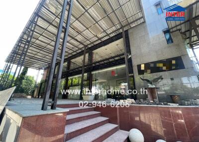 Entrance of a modern real estate building with glass doors and shaded portico