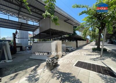 Spacious outdoor area under a shaded structure with potential for parking or storage, near a construction site