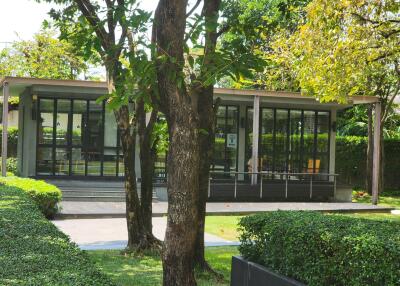 Modern glass-fronted building surrounded by lush greenery