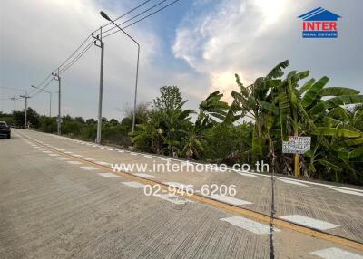 Wide road paving along a natural landscape, clear sky, with attributes for transportation near a property