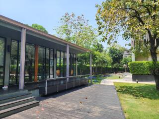 Modern building with large glass windows and a wooden deck overlooking a landscaped garden