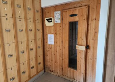 Wooden mailroom area with multiple mailboxes and glass door