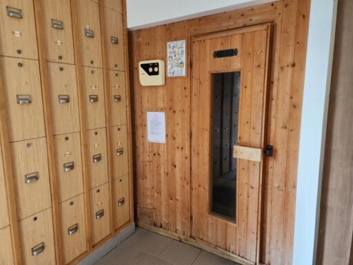 Wooden mailroom area with multiple mailboxes and glass door